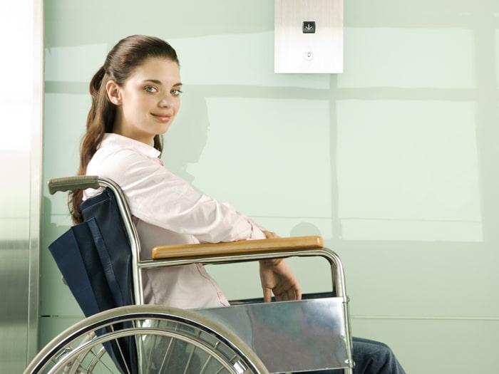 Behinderte Frau die auf den Aufzug wartet