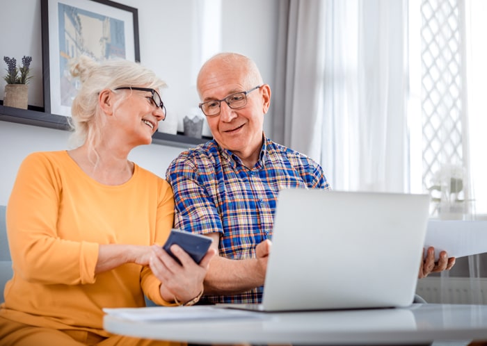 Paar prueft Rechnungen am Laptop